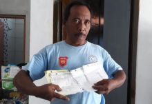 Muginarto memperlihatkan kwitansi pembayaran biaya berobat anaknya yang menjadi korban tsunami. Foto: int 