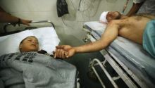 Seorang pria dewasa Palestina memegang tangan seorang bocah Palestina yang dirawat di sampingnya, di salah satu rumah sakit di Gaza. Saat ini, kondisi rumah sakit di kawasan itu semakin memprihatikan. Foto: int 