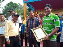 Bupati Pelalawan, H M Harris (berbaju kuning) menyerahkan penghargaan kepada SHR Manager RAPP Pelalawan, Mabrur atas kepedulian perusahaan bidang kesehatan./IST