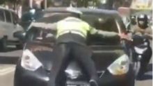 Petugas Polantas di Kota Bandung, bergelantungan di atas kap sebuah mobil karena berusaha menghentikan mobil yang melanggar aturan. Foto: int 