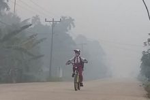 Seorang siswa bersepeda dengan kondisi kabut asap tebal. Foto: int 