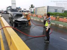 Petugas pemadam kebakaran saat memadamkan api dari Mitsubishi Xpander yang terbakar. (Foto: istimewa)