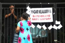 Trisnadi Marjan, mantan lurah Desa Kureksari, Sidoarjo, mencantolkan aplop di pagar rumahnya untuk diambil warga.Foto/SINDO MEDIA