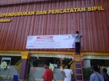 Petugas memasang spanduk himbauan di kantor Disdukcapil