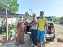 Ketua Kelompok KBR Berkah Hijau Mandiri, Anang Cahyono Ardi, menyerahkan bibit gratis saat kunjungan Camat Rumbai, Vemi Herliza. Foto: ist