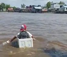 Viral bocah SD memperlihatkan seorang anak SD yang pulang sekolah memakai kardus di atas sungai.