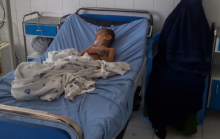 Seorang wanita Afghanistan duduk di sebelah seorang anak yang menerima perawatan di sebuah rumah sakit setelah dia terluka dalam ledakan bom di Kunduz pada hari Kamis