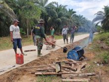 Personel Satgas TMMD kodim Bengkalis saat melakukan penyiraman aspal