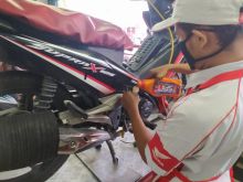 Petugas AHASS sedang melakukan pengisian oli ke sepeda motor konsumen di AHASS