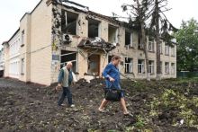 Penduduk setempat berjalan melewati sebuah bangunan yang rusak akibat penembakan di Chuhuiv, timur Kharkiv 