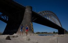 Orang-orang berjalan-jalan di dasar sungai Waal saat permukaan air turun karena kekeringan di Nijmegen, Belanda [Peter Dejong/AP Photo]