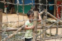 Seorang anak laki-laki terlihat di balik pagar kawat berduri di sebuah kamp pengungsi Rohingya di Bangladesh selatan [Sulyman Hossain/Al Jazeera]