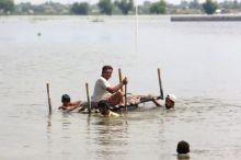Orang-orang menggunakan ranjang bayi untuk menyelamatkan barang-barang dari rumah mereka yang terendam banjir di Jaffarabad, sebuah distrik di provinsi Balochistan barat daya Pakistan [Fareed Khan/AP Photo]