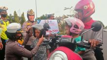 PS Kasubbid Kamsel Ditlantas Polda Riau, Kompol Birgitta Atvina memberikan helm pada anak-anak sebagai edukasi dalam berkendara. 