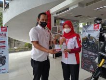 Petugas Dealer menyerahkan voucher gratis oli kepada konsumen setelah melakukan pembelian sepeda motor Honda di Dealer