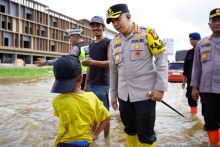 Kapolresta Pekanbaru Kombes Pol Jeki Rahmat Mustika mengobrol dengan seorang anak saat meninjau lokasi banjir di Sekitaran Jembatan Siak IV
