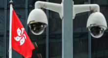 Bendera Hong Kong dikibarkan di belakang sepasang kamera pengintai di luar Kantor Pemerintah Pusat di Hong Kong /Reuters