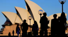 Orang-orang bersiluet di Sydney Opera House saat matahari terbenam di Australia /Reuters