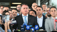 Mantan Presiden Brasil Jair Bolsonaro berbicara kepada media di sebelah putranya Senator Flavio Bolsonaro (C-Right), setelah meninggalkan gedung Senat di Brasilia pada 26 Maret 2025 /AFP