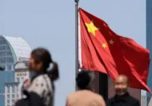 Bendera nasional Tiongkok berkibar saat orang-orang berjalan di jembatan penyeberangan di Shanghai, Tiongkok, 15 April 2025 /Reuters