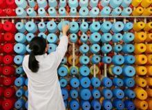 Seorang karyawan mengatur gelendong di sebuah pabrik tekstil di kabupaten Haian, provinsi Jiangsu, China /Reuters