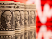 ang kertas satu dolar AS terlihat di depan grafik saham yang ditampilkan dalam ilustrasi ini /Reuters