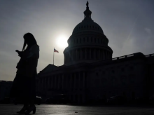 Seseorang menggunakan ponsel dengan latar belakang Gedung Capitol AS di Capitol Hill, Washington /Reuters