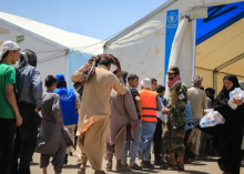 Foto yang diambil pada 24 Juli 2025 ini menunjukkan migran Afghanistan yang baru tiba yang dideportasi dari Iran, berdiri dalam antrian di luar tenda kemanusiaan untuk menerima paket makanan dari Omid Haqjoo (tidak ada foto), seorang sukarelawan Afghanistan di perbatasan Islam Qala di provinsi Herat