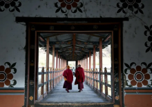 Dalam foto yang diambil pada 10 Januari 2024 ini, para biksu Buddha berjalan melintasi jembatan kayu di ibu kota Bhutan, Thimphu/ AFP
