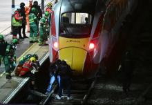 Petugas polisi dan anggota layanan darurat memeriksa rel di bawah kereta LNER Azuma di Stasiun Huntingdon di Huntingdon, Inggris timur, pada 1 November 2025, setelah penusukan di dalam kereta/ AFP